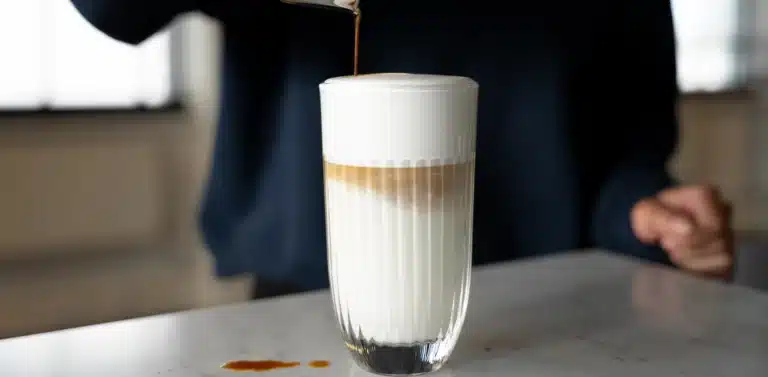 Latte macchiato in een hoog glas met een persoon er achter