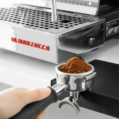 Pistol met koffie naast een La Marzocco espresso machine
